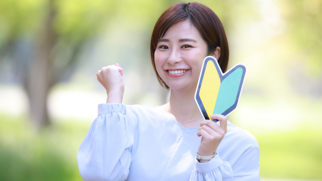 初心者マークを持って笑顔でガッツポーズする女性の写真