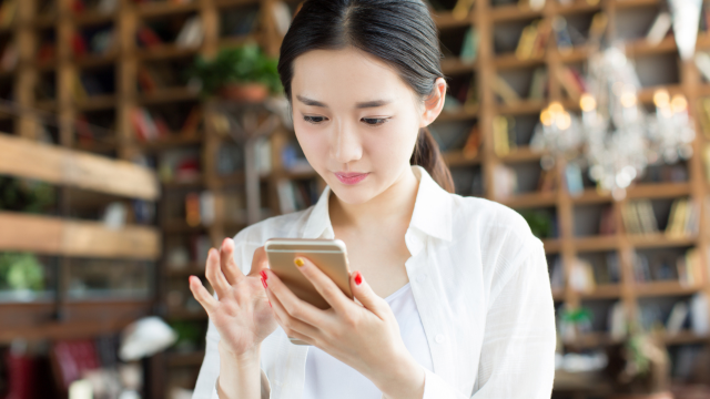スマホをタップする女性の写真